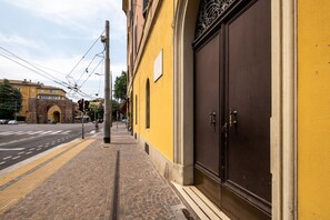 A street with a yellow building, a large dark door, and a brick archway in the background. - Mazzini Elegant Apartment by Wonderful Italy (Bologna)