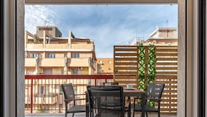 Un balcón con una mesa y sillas, con vistas a una zona residencial con edificios y una valla de madera.