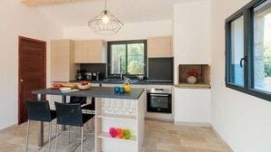 Une cuisine moderne avec un îlot central, des chaises noires et un luminaire suspendu.
