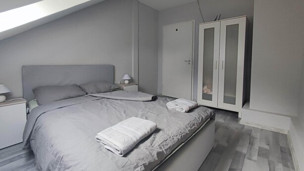 Ein modernes Schlafzimmer mit einem großen Bett, einem Nachttisch, einem Kleiderschrank und einem Oberlicht.