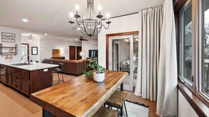 A modern kitchen with a wooden island, pendant lighting, and a view through a large window.