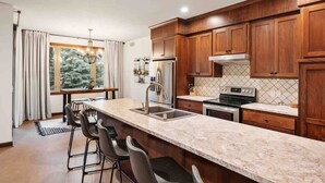 A modern kitchen with wooden cabinets, a marble countertop, and a large window.