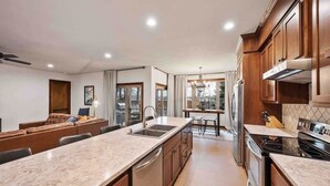 A modern kitchen with a central island, stainless steel appliances, and wooden cabinetry.
