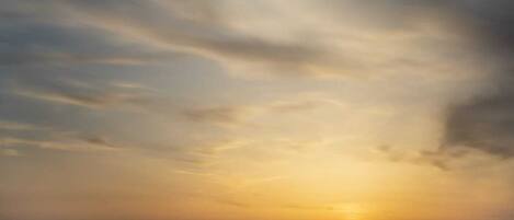 A sunset over a calm body of water with distant landforms.