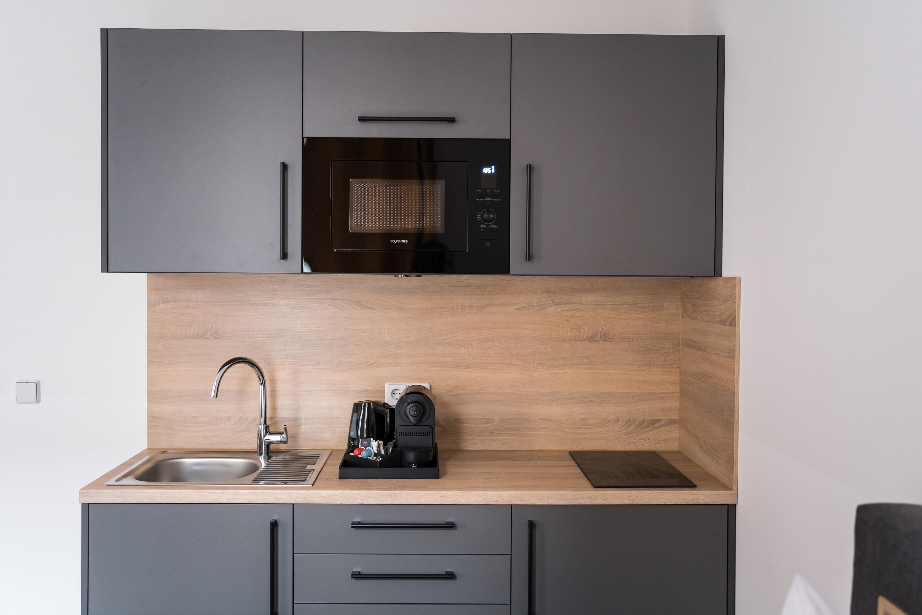 A modern kitchen with a built-in microwave, a coffee maker, and a sink.