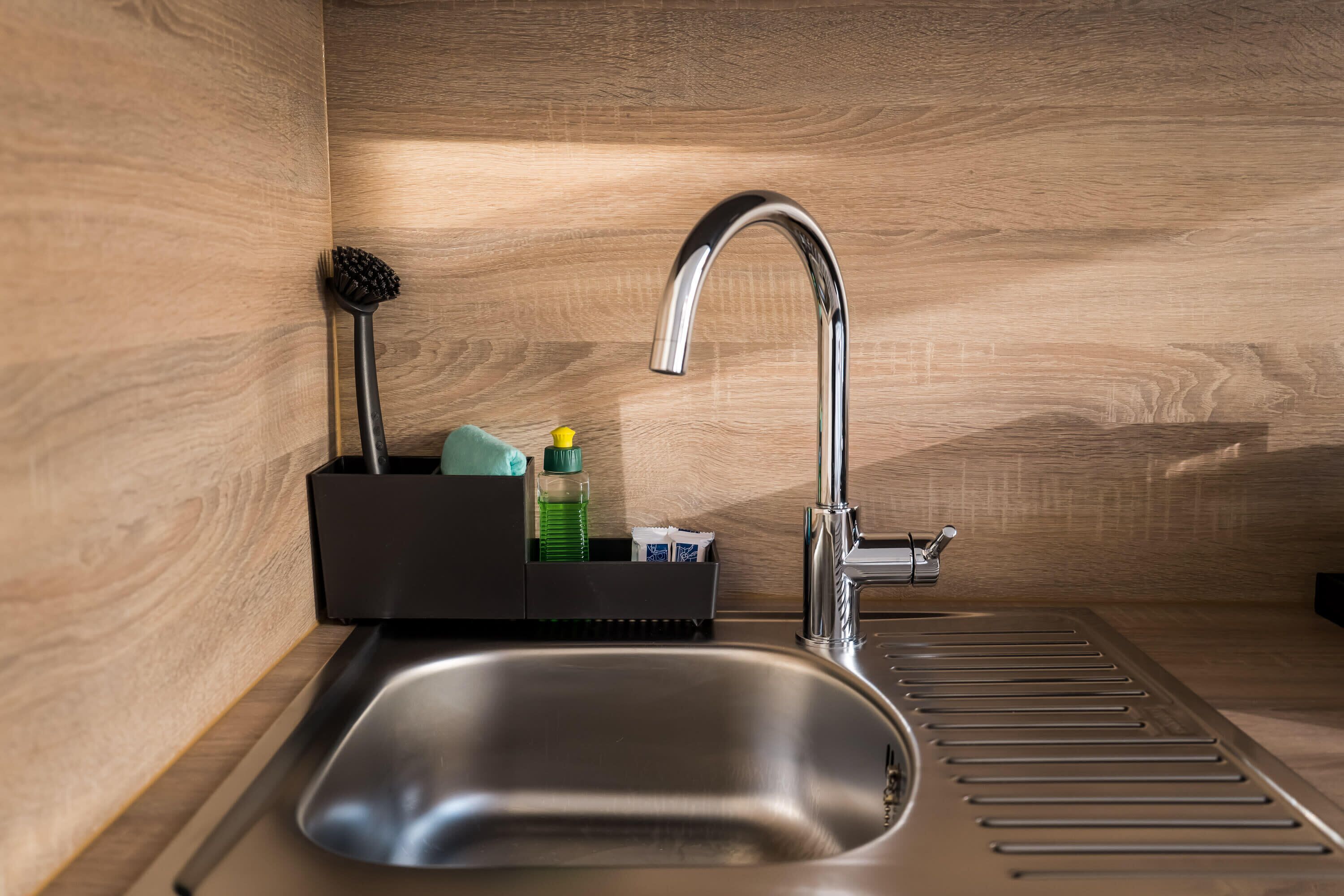 Una cocina moderna con un lavamanos de acero inoxidable, un grifo y un dispensador de jabón.