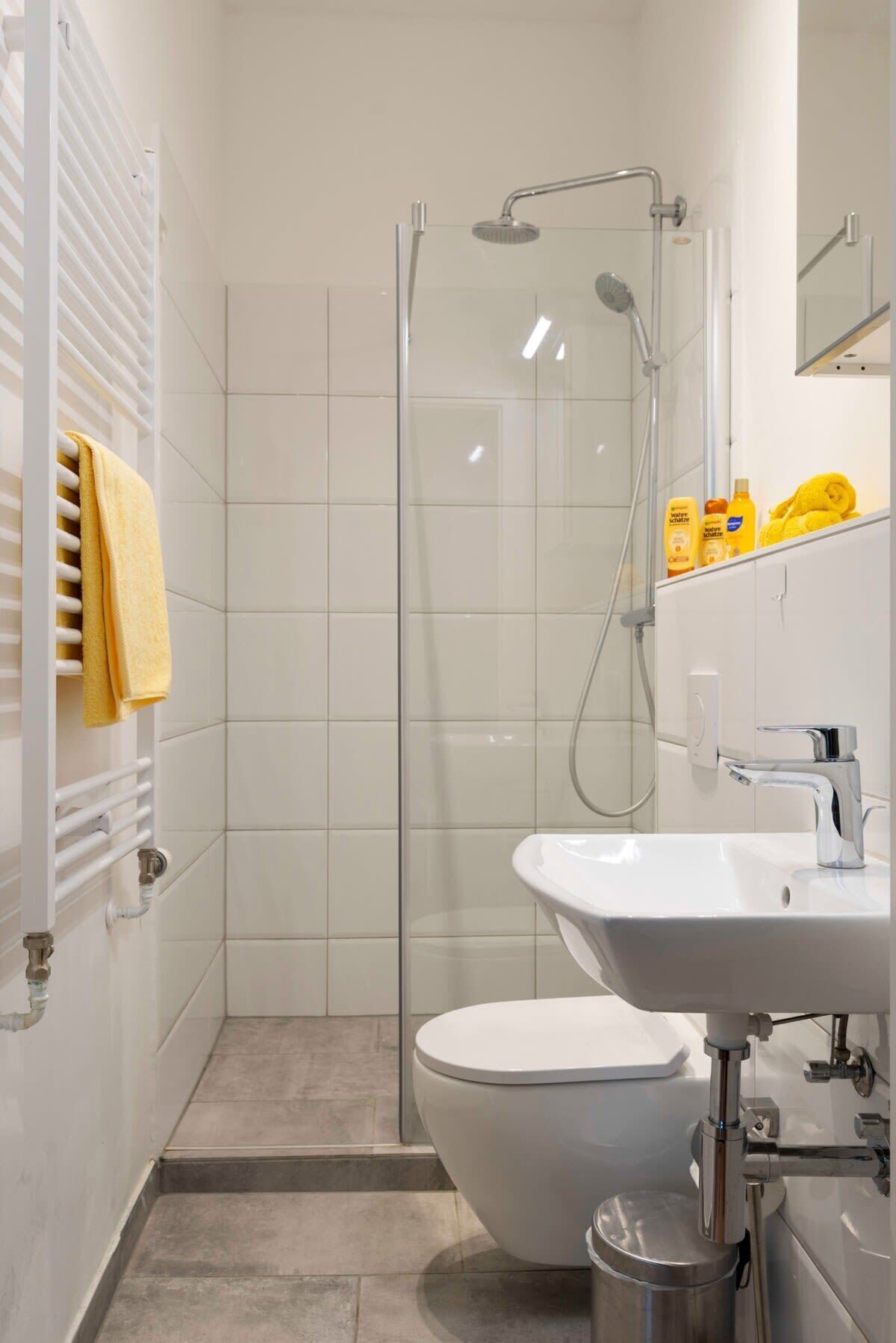 A modern bathroom with a glass-enclosed shower, a white sink, and a toilet.