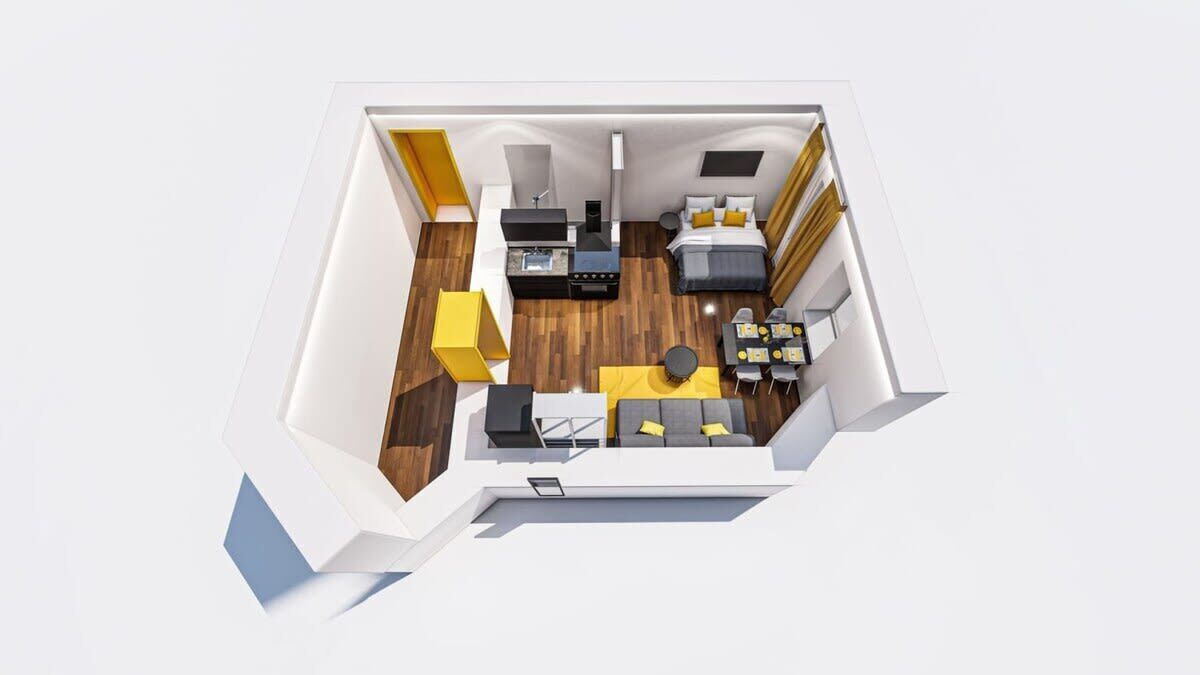 A 3D floor plan of a modern hotel room with a bed, desk, chair, and a small seating area.