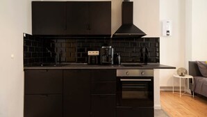 A modern kitchen with black cabinets, a black countertop, a coffee maker, and a built-in oven. - Lovely Apartment in the near of Kudamm (Berlin)