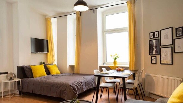 A modern room with a bed, a dining table, and a TV. - Lovely Apartment in the near of Kudamm (Berlin)