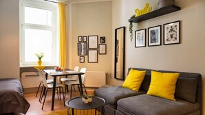 A modern living room with a sofa, a dining table, and a window with curtains. - Lovely Apartment in the near of Kudamm (Berlin)