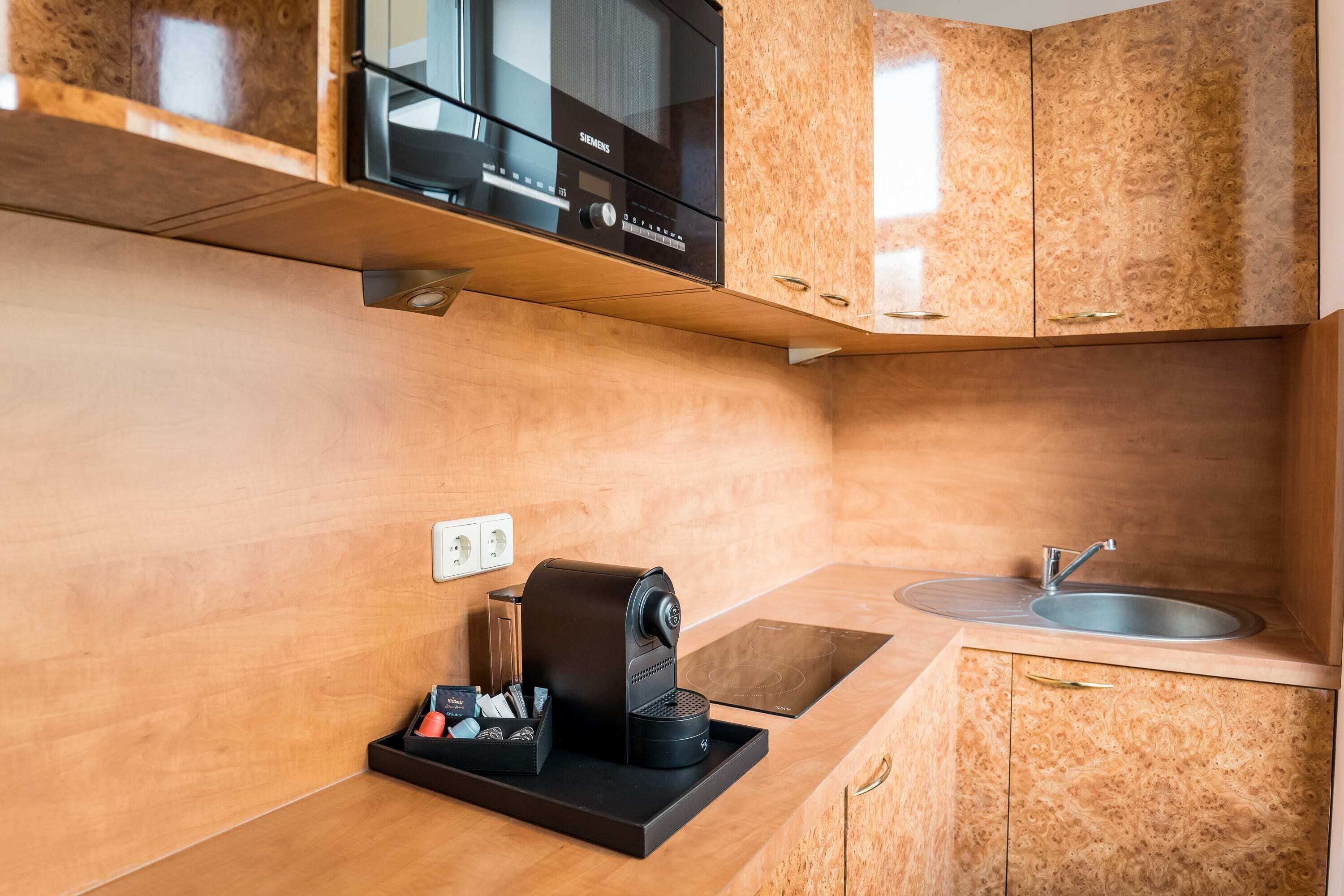 A compact kitchen with a built-in microwave, a coffee machine, and a sink.