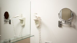 A bathroom with a glass sink, a hairdryer, a mirror, and a wall-mounted telephone. - Boxi Studios Berlin S (Berlin)