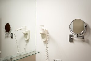 A bathroom with a glass sink, a hairdryer, a mirror, and a wall-mounted telephone. - Boxi Studios Berlin S (Berlin)