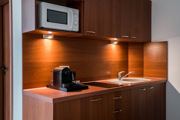 Una cocina moderna equipada con microondas, cafetera y lavamanos.