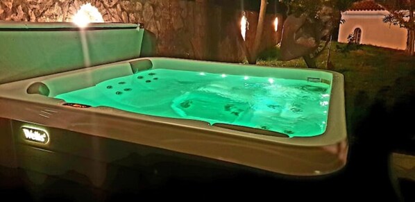 A hot tub with a control panel, surrounded by a stone wall and a small building in the background. - Cottage with Private Pool (POROS)