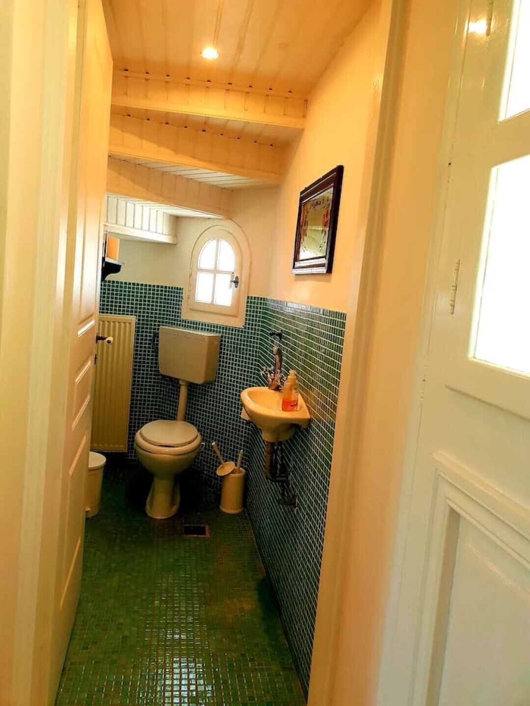 Une petite salle de bain avec des toilettes, un lavabo et des murs carrelés.