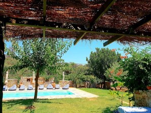 A pool area with lounge chairs and a pergola overhead. - Cottage with Private Pool (POROS)