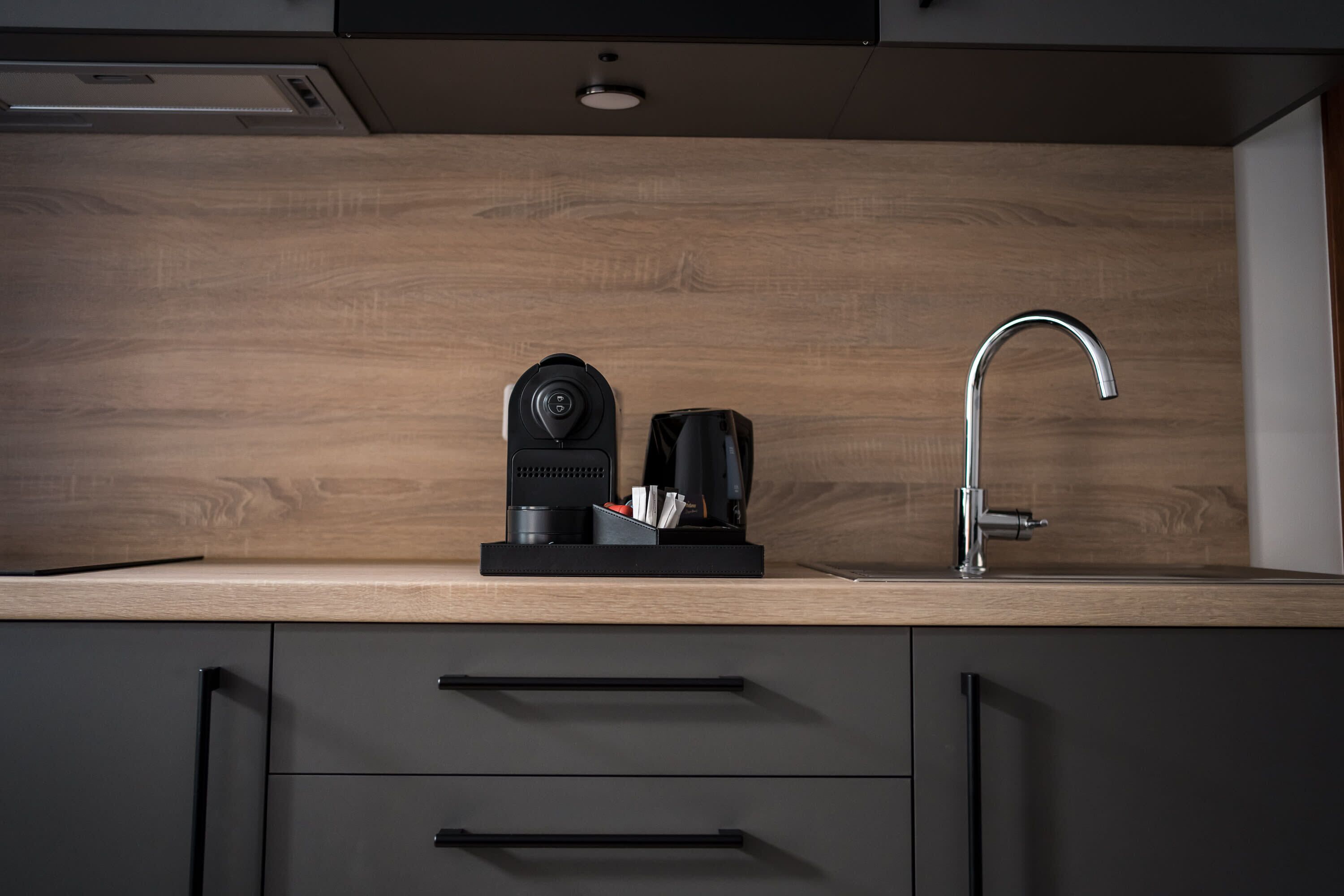 A modern kitchen with a wooden countertop, a coffee maker, a toaster, and a stainless steel faucet.