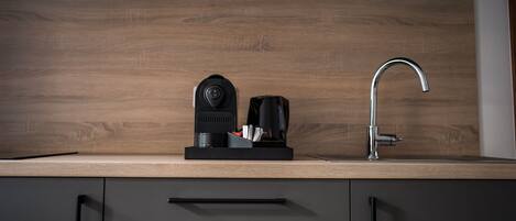 A modern kitchen with a wooden countertop, a coffee maker, a toaster, and a stainless steel faucet.