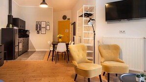 A modern living room with a fireplace, a dining area, and a TV mounted on the wall. - Great Apartment close to Kudamm (Berlin)