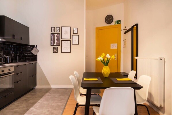 A modern kitchen with dark cabinets and a dining area with a yellow vase of flowers.