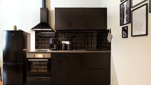 A modern kitchen with dark cabinetry, a built-in oven, and a coffee maker. - Great Apartment close to Kudamm (Berlin)