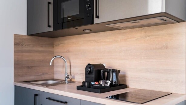 A modern kitchen with a wooden countertop, a coffee machine, and a sink.
