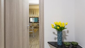 A modern interior with a wooden door, a vase of yellow tulips, and two green bowls on a black shelf. - XXV Aprile - Basilico by Wonderful Italy (Genoa)