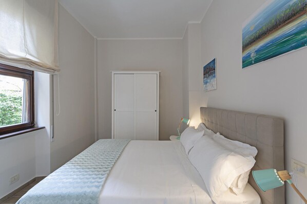 Une chambre à coucher avec un lit, une fenêtre, une porte et un tableau au mur.