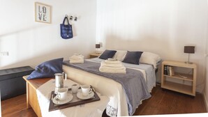 A neatly arranged bedroom with a bed, bedside tables, a coffee table, and a wall-mounted bag. - Salomone Apt 8 With Balcony by Wonderful Italy (Syracuse)