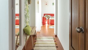 A hallway with a wooden door, a bench, a rug, and a red sofa in the background. - Salomone Apt 8 With Balcony by Wonderful Italy (Syracuse)