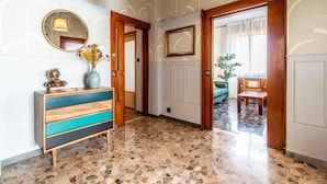 A hallway with a wooden door, a mirror, a vase with flowers, and a green sofa. - Dimora Vintage San Tommaso by Wonderful Italy (Bologna)