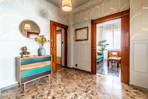 A hallway with a wooden cabinet, a mirror, and a vase with flowers. - Dimora Vintage San Tommaso by Wonderful Italy (Bologna)
