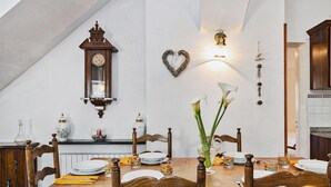 A dining room with a wooden table set for four, a wall-mounted clock, and a heart-shaped decoration. - Villa Rica by Wonderful Italy (Santa Margherita Ligure)
