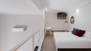 A bedroom with a bed, a desk, and a chair.
