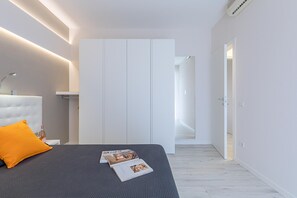 Ein modernes Schlafzimmer mit einem Bett, einem Nachttisch, einer Zeitschrift und einem Kleiderschrank.