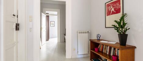 A hallway with a bookshelf, a radiator, and a framed picture on the wall.