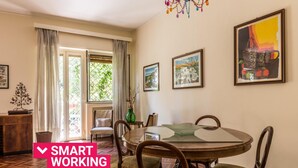 A dining area with a round table, chairs, and a chandelier. There are framed pictures on the wall and a window with curtains. - Un Giardino Segreto a Palermo by Wonderful Italy (Palermo)