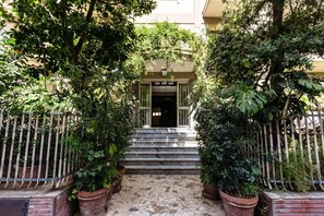 L’entrée d’un immeuble, avec un escalier en pierre menant à une porte.