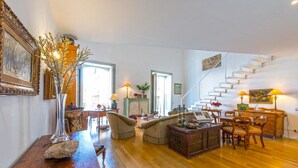 A spacious living room with a wooden floor, a staircase, and a dining area. - Charming Apartment by Wonderful Italy (Palermo)