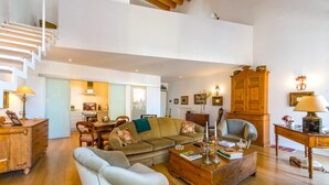 A spacious living room with a high ceiling, a staircase, a wooden cabinet, and a dining area. - Charming Apartment by Wonderful Italy (Palermo)