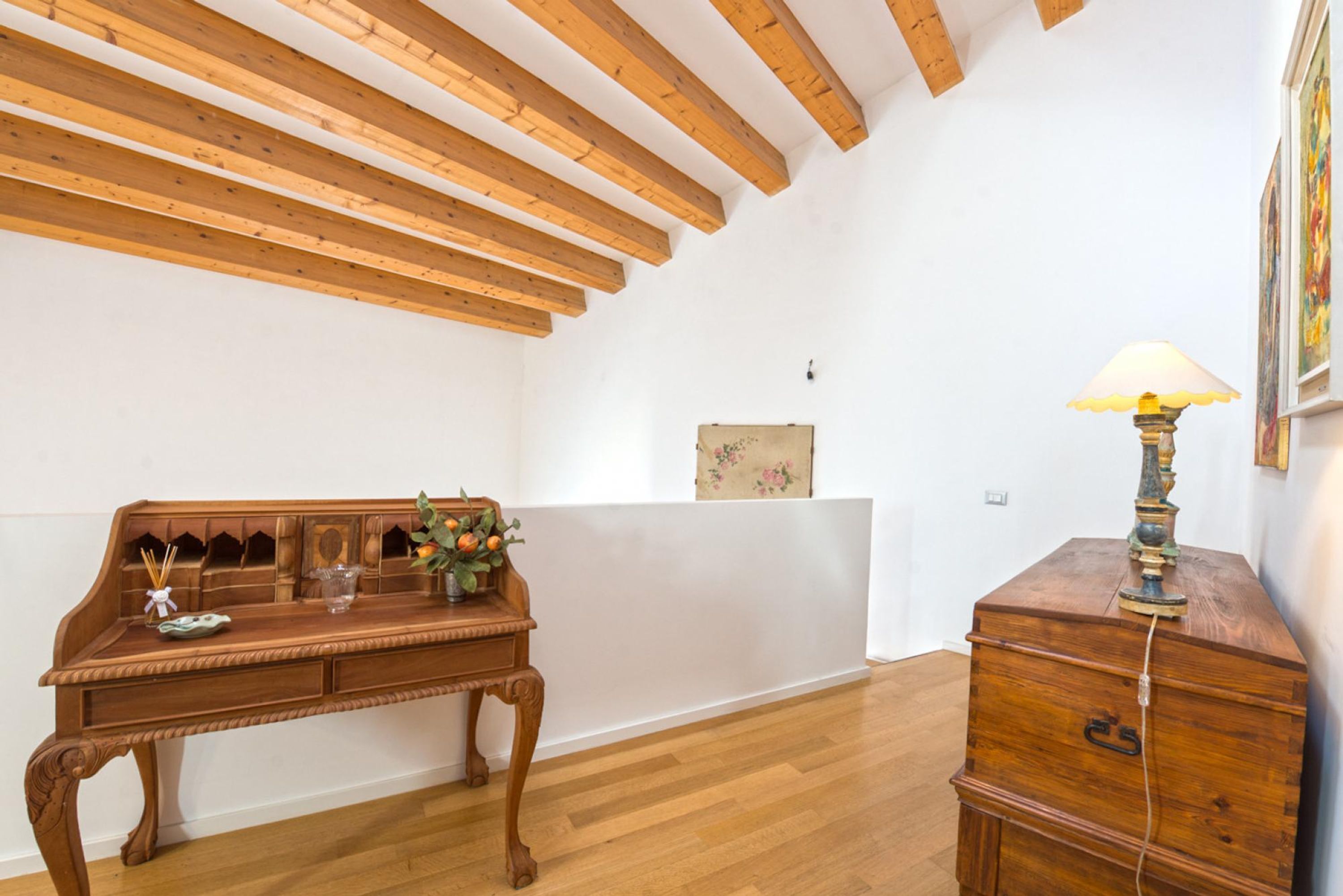 Een kamer met een houten bureau, een lamp en een dressoir.