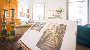 A book with photographs of a stone staircase and a building, placed on a wooden table in a room with a wooden cabinet and a sofa. - Charming Apartment by Wonderful Italy (Palermo)