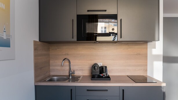 A modern kitchen with a built-in microwave, a sink, and a coffee maker on the countertop. - Boxi Studios Berlin S (Berlin)