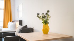 A modern living room with a yellow vase on a wooden table, a sofa, and a chair. - Boxi Studios Berlin S (Berlin)