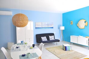 Un salon moderne avec un coin repas, comprenant un canapé, un meuble blanc et un mur d’accent bleu.