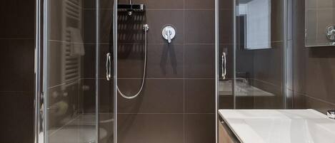 Un baño moderno con ducha acristalada, un lavabo espacioso y un espejo.