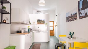 Une cuisine de taille réduite avec des meubles blancs, un évier et un coin repas doté de chaises jaunes.