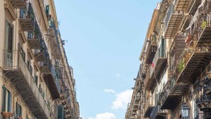 Une rue bordée d’immeubles à plusieurs étages, chacun doté de balcons et d’espaces aménagés pour s’asseoir à l’extérieur.